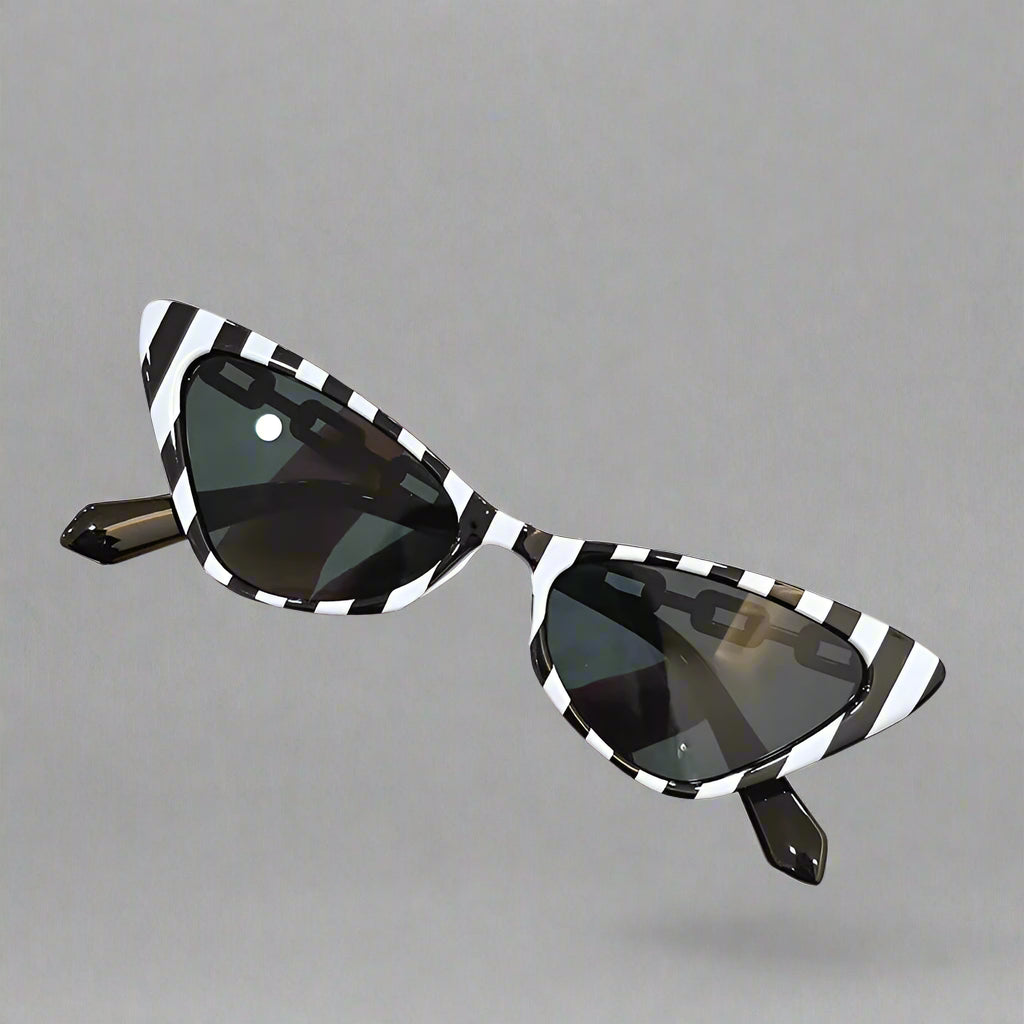 Black and white striped sunglasses held by a hand against a neutral background