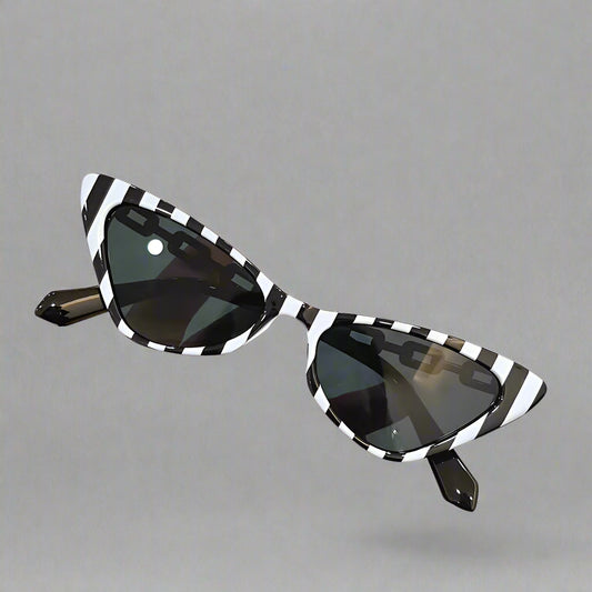 Black and white striped sunglasses held by a hand against a neutral background